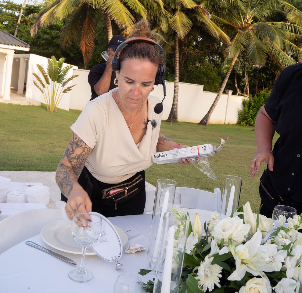 Anni Roth preparing a reception table under palm trees, Dominican Republic
