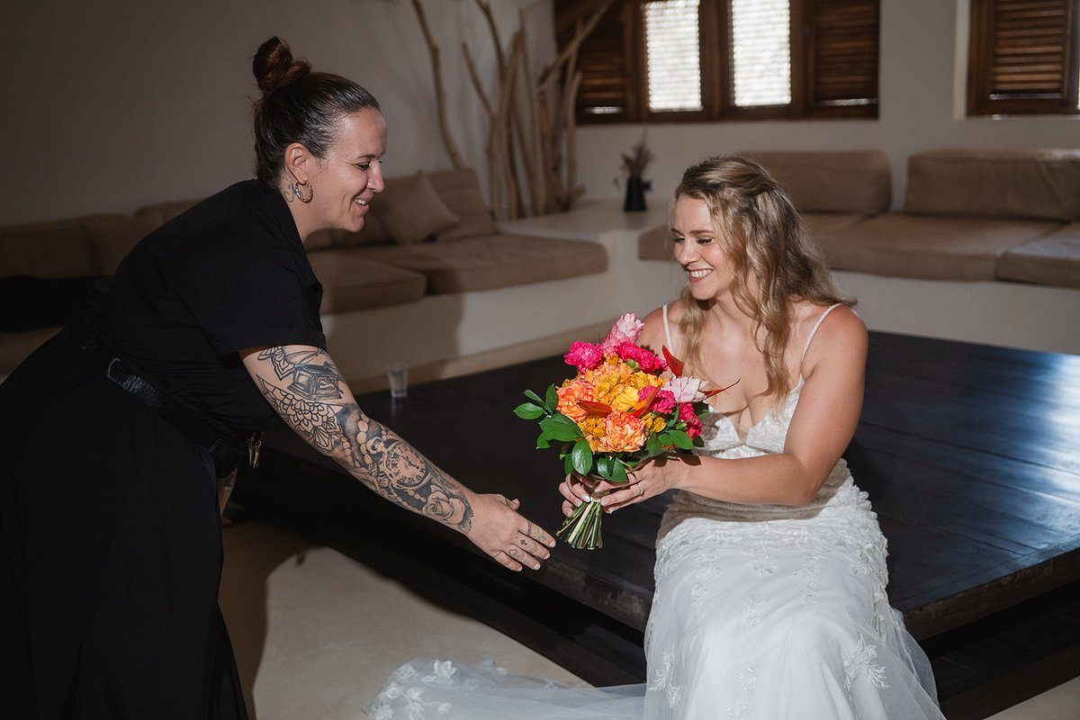 Wedding planner handing bride her bouquet in golden light