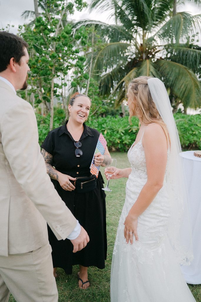 Wedding planner speaking with the bride and groom outdoors surrounded by palm trees