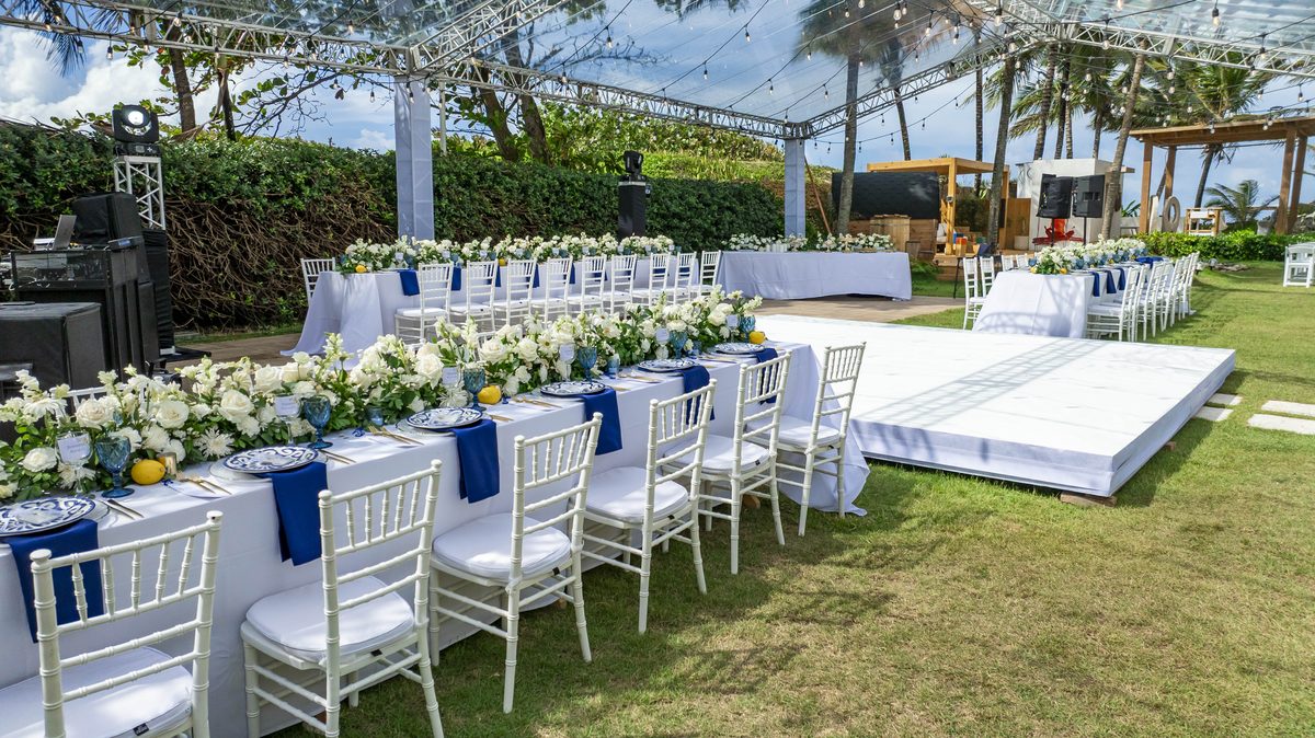 Outdoor wedding reception setup with white chiavari chairs and floral table settings